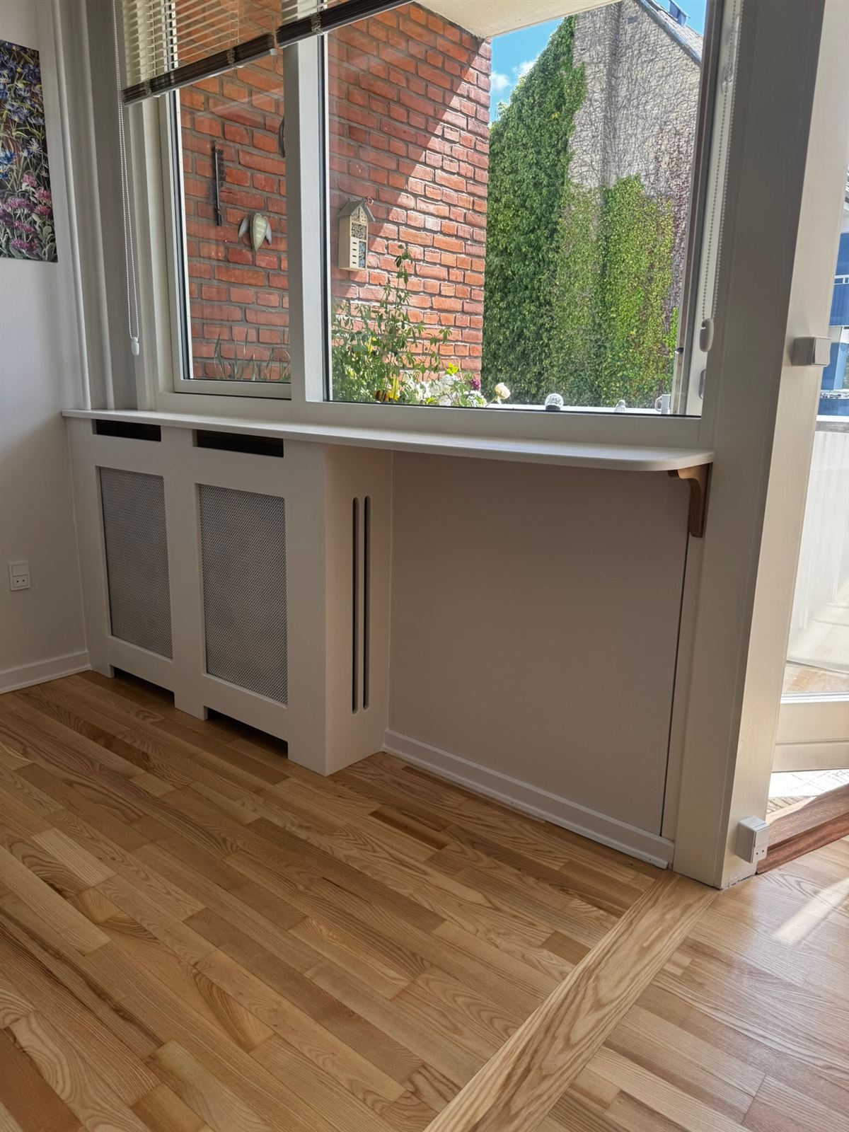 Hvid radiatorskjuler bygget under vindue